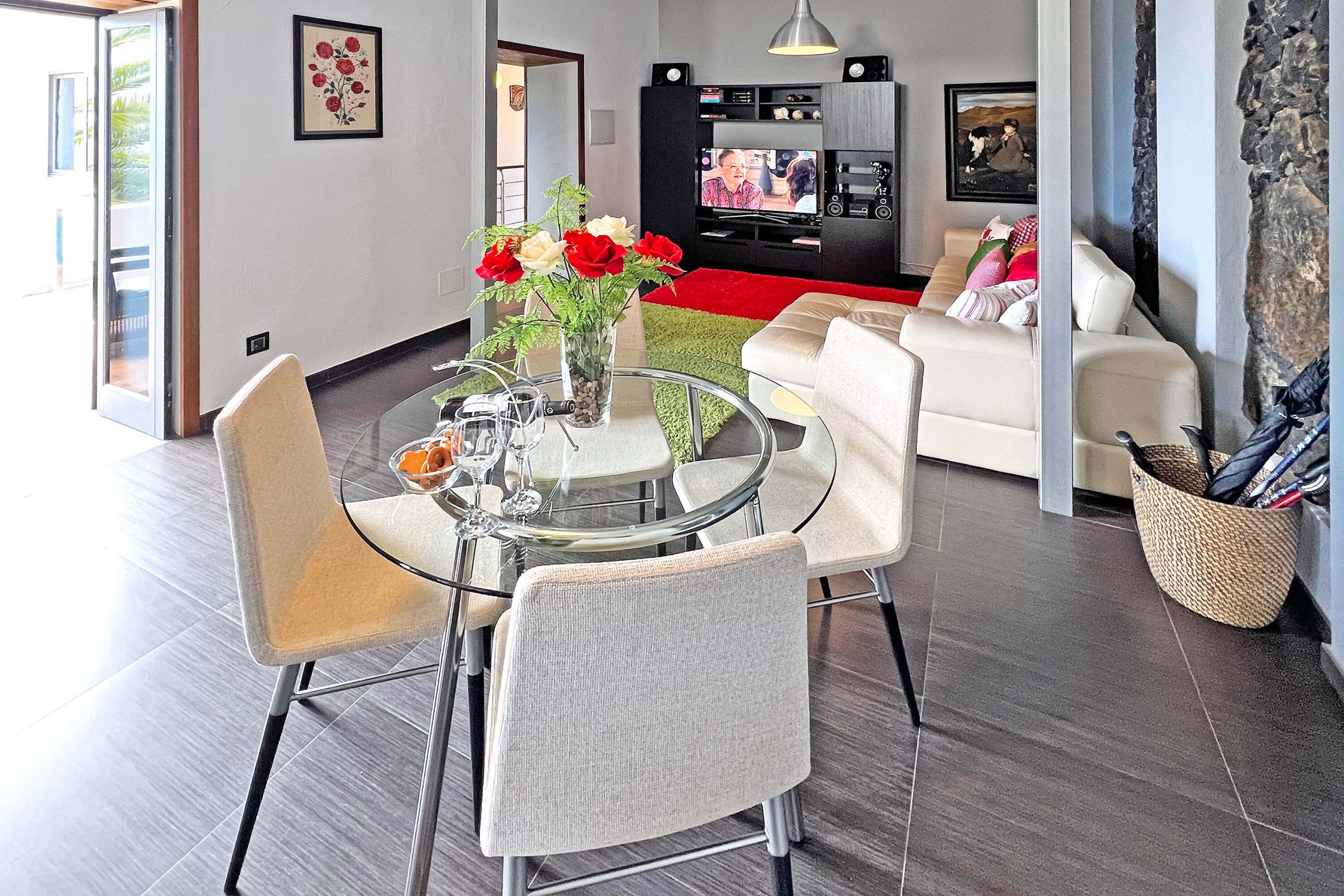 A modern living room with a dining area, a flat-screen TV, and a stone accent wall.