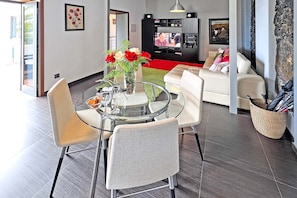 A modern living room with a dining area, a flat-screen TV, and a stone accent wall. - Villa Gamonal en Tijarafe (Tijarafe)