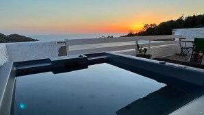 A swimming pool with a view of the sunset and a white fence.