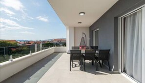 A balcony with a table and chairs, a view of houses, and a clear sky. - Villa David (Kastel Lukšić)