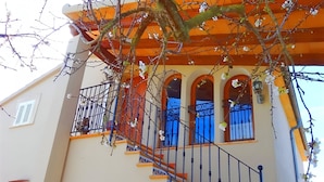 A building with a staircase leading to an upper floor, a balcony with a railing, and a window with a blue curtain. - Son Antem 420 fantastic finca with private pool, terrace, barbecue and air conditioning (Llucmajor)