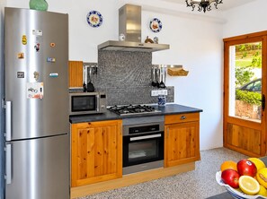 A kitchen with a stainless steel refrigerator, microwave, stove, and oven. There are wooden cabinets and a tiled backsplash. A fruit bowl is on the counter. - Son Antem 420 fantastic finca with private pool, terrace, barbecue and air conditioning (Llucmajor)