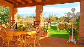 An outdoor patio with a table set for dining, surrounded by wicker chairs, and a view of a swimming pool and garden. - Son Antem 420 fantastic finca with private pool, terrace, barbecue and air conditioning (Llucmajor)