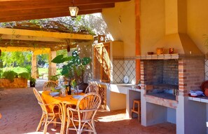 An outdoor patio with a brick barbecue, wicker furniture, and a table set for dining. - Son Antem 420 fantastic finca with private pool, terrace, barbecue and air conditioning (Llucmajor)