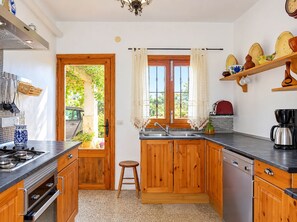 Eine Küche mit Holzausstattung, einem Herd, einem Spülbecken und einem Fenster mit Vorhängen.