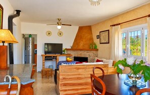 Eine moderne Küche mit eingebautem Ofen, ein Essbereich mit einem Holztisch und Stühlen, einem Fernseher und einem Kamin.