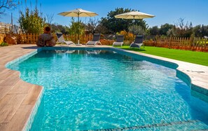 A swimming pool with clear blue water, surrounded by lounge chairs and umbrellas. - Son Antem 420 fantastic finca with private pool, terrace, barbecue and air conditioning (Llucmajor)