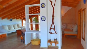 A cozy living room with a high wooden ceiling, a white wall with decorative plates, a wooden bench, and a sofa with cushions. - Son Antem 420 fantastic finca with private pool, terrace, barbecue and air conditioning (Llucmajor)