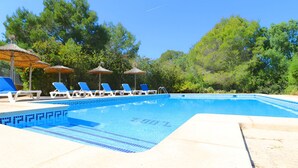 A swimming pool with blue tiles, white lounge chairs, and thatched umbrellas. - Can Palea 407 finca with private pool with garden, terrace, barbecue and WiFi (Campos)