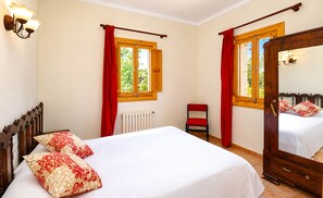 A bedroom with a bed, a chair, a radiator, and a mirror. - Can Palea 407 finca with private pool with garden, terrace, barbecue and WiFi (Campos)