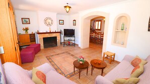 A living room with a fireplace, sofas, a TV, and a dining area. - Can Palea 407 finca with private pool with garden, terrace, barbecue and WiFi (Campos)