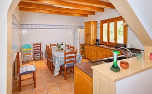 Una cocina con armarios de madera, una mesa de comedor con sillas y un salpicadero de azulejos.