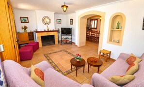 A living room with a fireplace, sofa, TV, and dining area. - Can Palea 407 finca with private pool with garden, terrace, barbecue and WiFi (Campos)