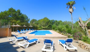 Un área de piscina con sillones de descanso y una piscina azul cristalina.