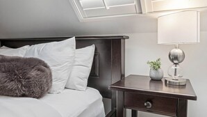 Une chambre d’hôtel moderne avec un lit bien fait, une table de chevet avec une lampe et une petite plante.