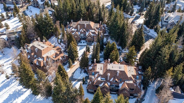 Vue aérienne d’un quartier résidentiel composé de nombreuses maisons, entourées d’une forêt dense de conifères.