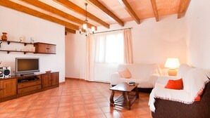 Ein Wohnzimmer mit Fernseher, Holzschränken, einer Couch, einem Couchtisch und einer Lampe.