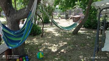 Relax in a hammock suspended between trees, surrounded by lush grass and leaves, and enjoy a game of volleyball.