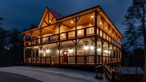 Una baita di legno a due piani con un balcone, ampie finestre e una porta rossa.