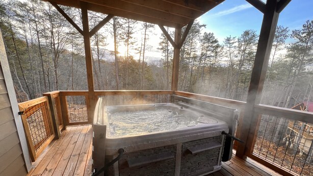Una vasca idromassaggio su un pontile di legno con vista su una foresta.