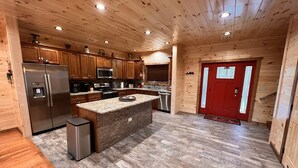 Una cucina moderna con mobili in legno, un frigorifero in acciaio inossidabile, un forno a microonde e una porta rossa.