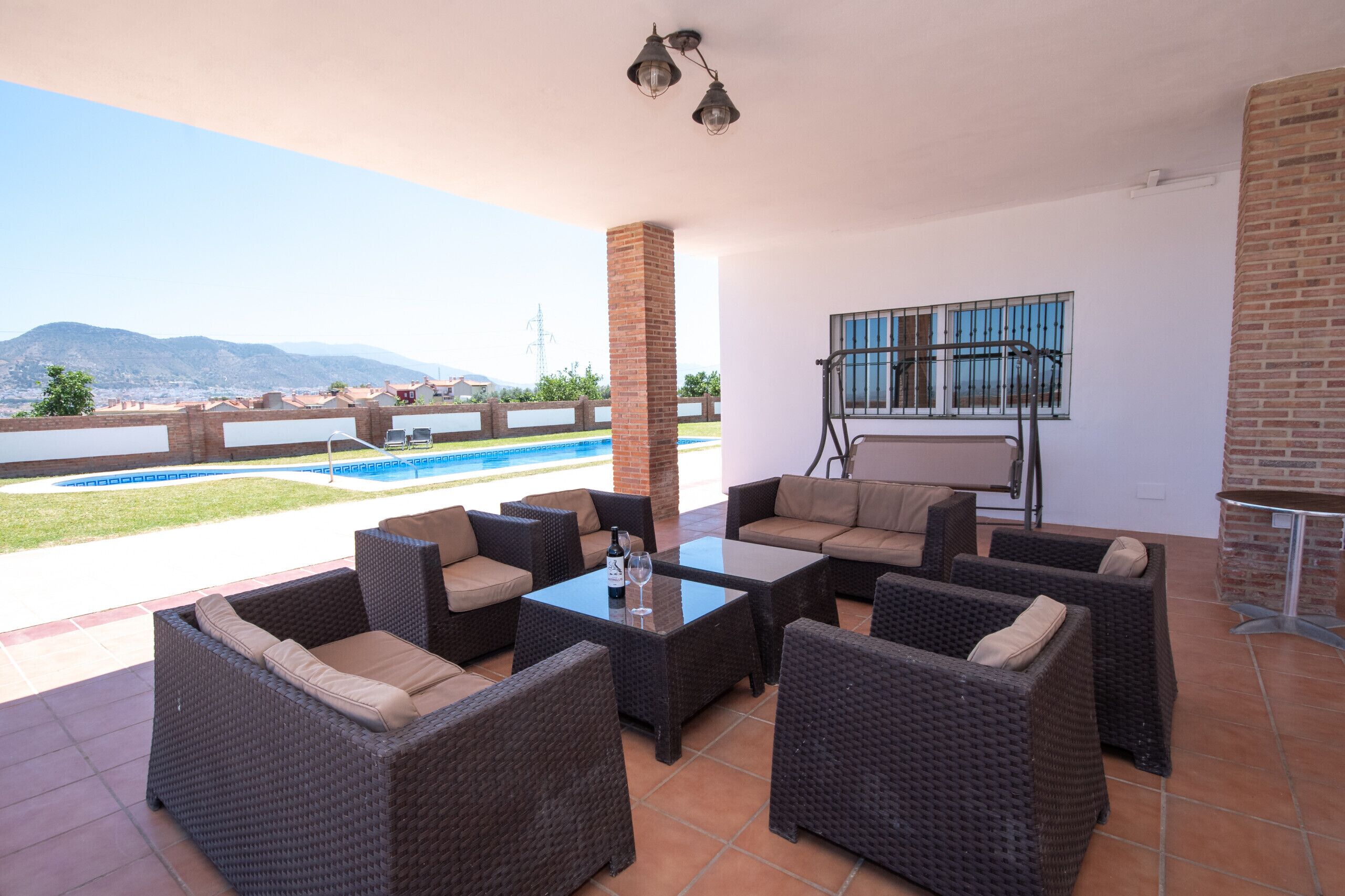 Un espacio al aire libre con patio, muebles de mimbre, piscina y vistas a las montañas.