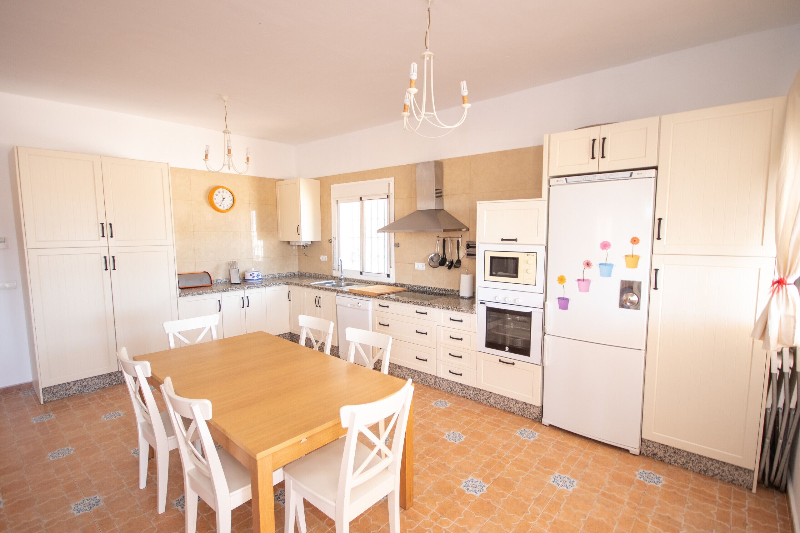 A kitchen with white cabinets, a wooden table, and chairs.