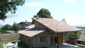 A stone house with a tiled roof, a patio with outdoor furniture, and a view of the countryside. - Family cottage with terrace, pets welcome (Chuyer)