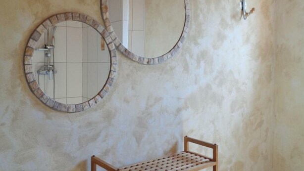 A bathroom with two round mirrors with brick frames, a wooden bench, and a wall-mounted light fixture. - Family cottage with terrace, pets welcome (Chuyer)