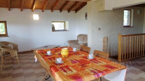 A dining area with a table set for four, a sofa, and a wooden railing. - Family cottage with terrace, pets welcome (Chuyer)
