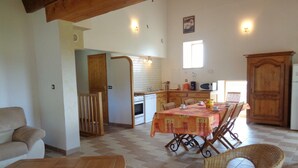 A spacious living area with a wooden table and chairs, a sofa, and a kitchen in the background. - Family cottage with terrace, pets welcome (Chuyer)