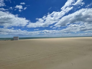 A beach with a lifeguard tower and a clear sky.