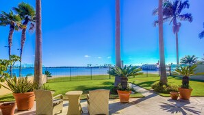 Eine Terrasse mit Korbmöbeln, Topfpflanzen und Blick auf das Meer.