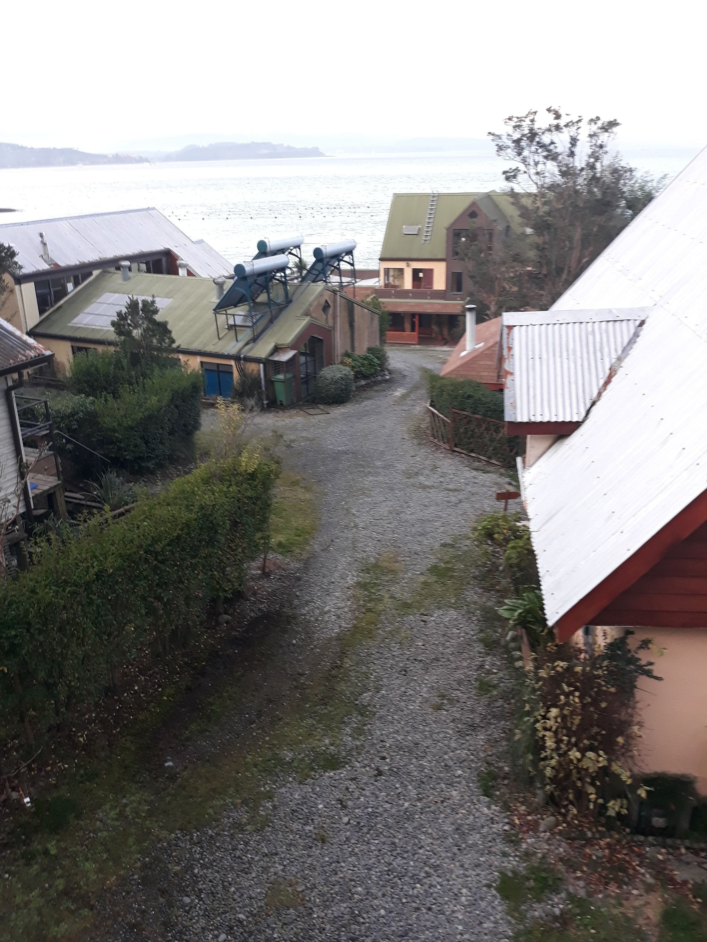 A gravel path leading to a building with a green roof and a metal staircase.