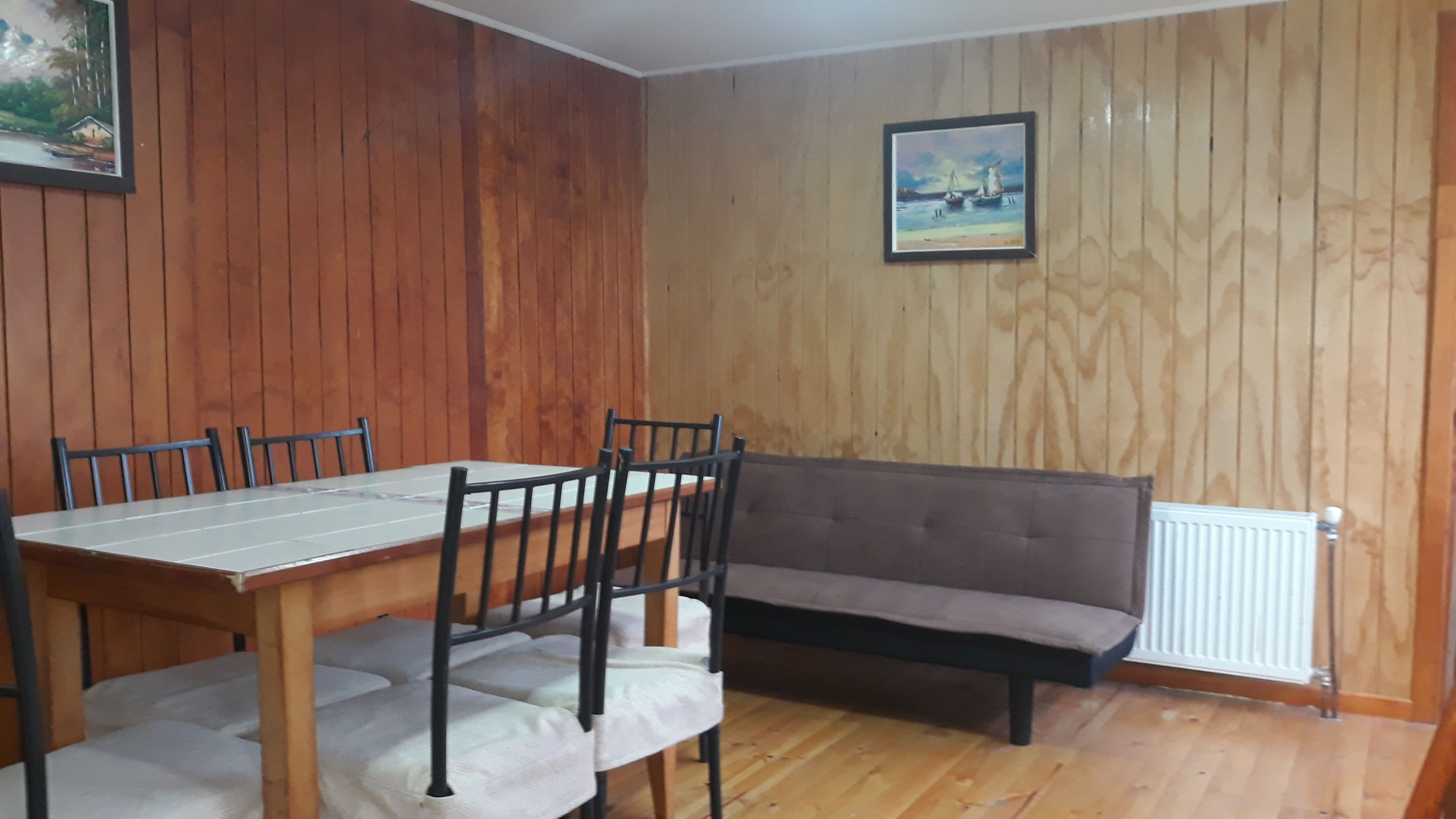 Zona pranzo con tavolo e sedie in legno, un divano e pareti in legno.