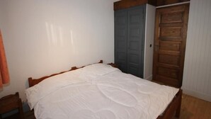 A bedroom with a wooden bed, a wardrobe, and a door. - Cozy apartment in Les Saisies - 6 pers, fireplace, south balcony (Les Saisies)
