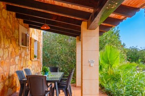 An outdoor patio with a table and chairs, a stone wall, and a sign with text. - Can Toni 403 traditional finca with private pool, air-conditioning, large garden and WiFi (Campos)