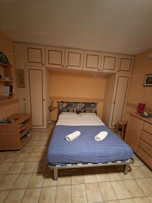 A bedroom with a bed, a nightstand, a chair, and built-in cabinets.