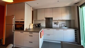 A modern kitchen with stainless steel appliances, white cabinetry, and a large window. - 4EGA41 - Superb F3 in the city center (COLLIOURE)
