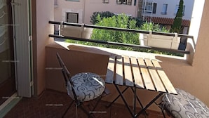 Un balcón con una silla y una mesa, con vista a una zona residencial con varios edificios.