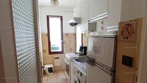 Una cocina compacta con lavadora, refrigerador y ventana con vistas.
