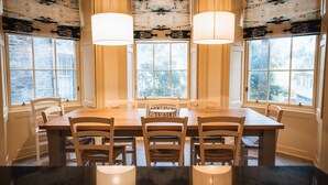 A dining area with a wooden table, four chairs, and two pendant lights.