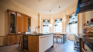 A kitchen with wooden cabinets, a central island, and a dining area with chairs.