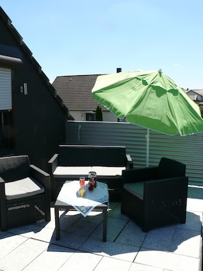 A patio with wicker furniture, a table with a tablecloth, and a green umbrella. - 2 rooms, kitchen, bathroom (full equipment), terrace (Weiskirchen)
