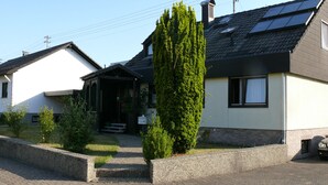 Een woonhuis met een schuin dak, zonnepanelen en een verzorgde tuin.
