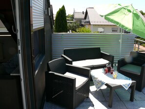 An outdoor patio with wicker furniture, a table with a tablecloth, and a green umbrella. - 2 rooms, kitchen, bathroom (full equipment), terrace (Weiskirchen)