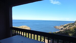 En balkon med udsigt over havet og en klippefyldt kystlinje.