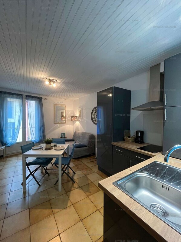 A modern kitchen with a built-in sink, a dining area with a table and chairs, and a living space with a sofa.