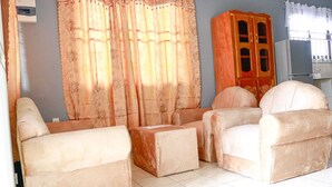 A living room with beige sofas, a wooden cabinet, and a window with curtains. - Abidager 2  ideal for family with children and groups (Wanica)