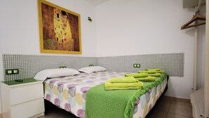 Siististi järjestetty hotellihuone, jossa on sänky, työpöytä ja suuri taulu seinällä.